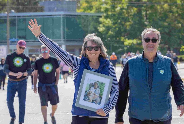 Photo of Debbie, former client of DSORC, at the 2025 Walk for Dementia. Debbie is holding a portrait of her mom, who passed away in early 2025.